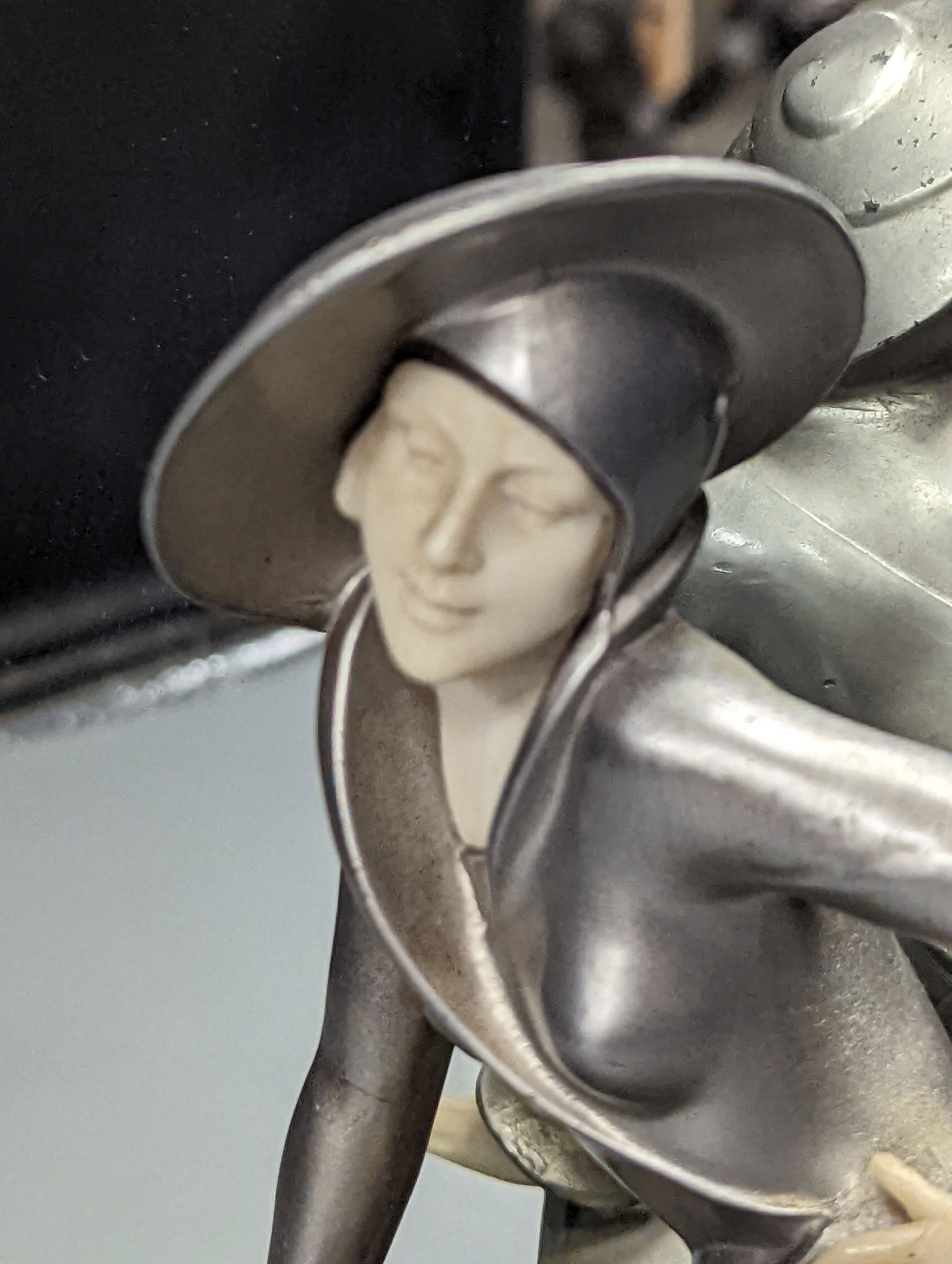 An Art Deco style patinated spelter and faux ivory figural mantel mirror, 31cm